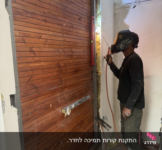 אדם מרתך מסגרת עץ עם קסדה וכלים.
